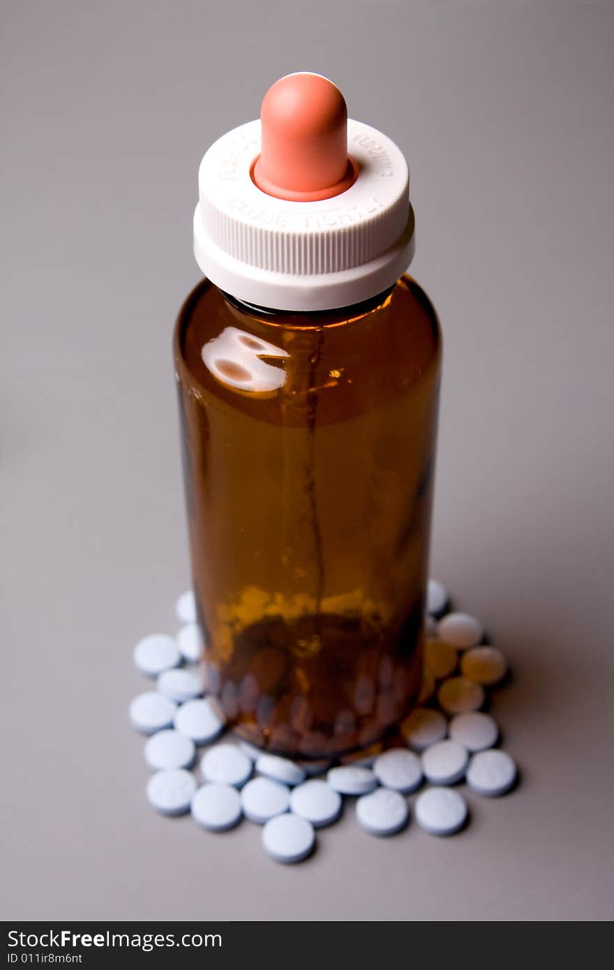 The medicine bottle is surrounded by tablets. The medicine bottle is surrounded by tablets