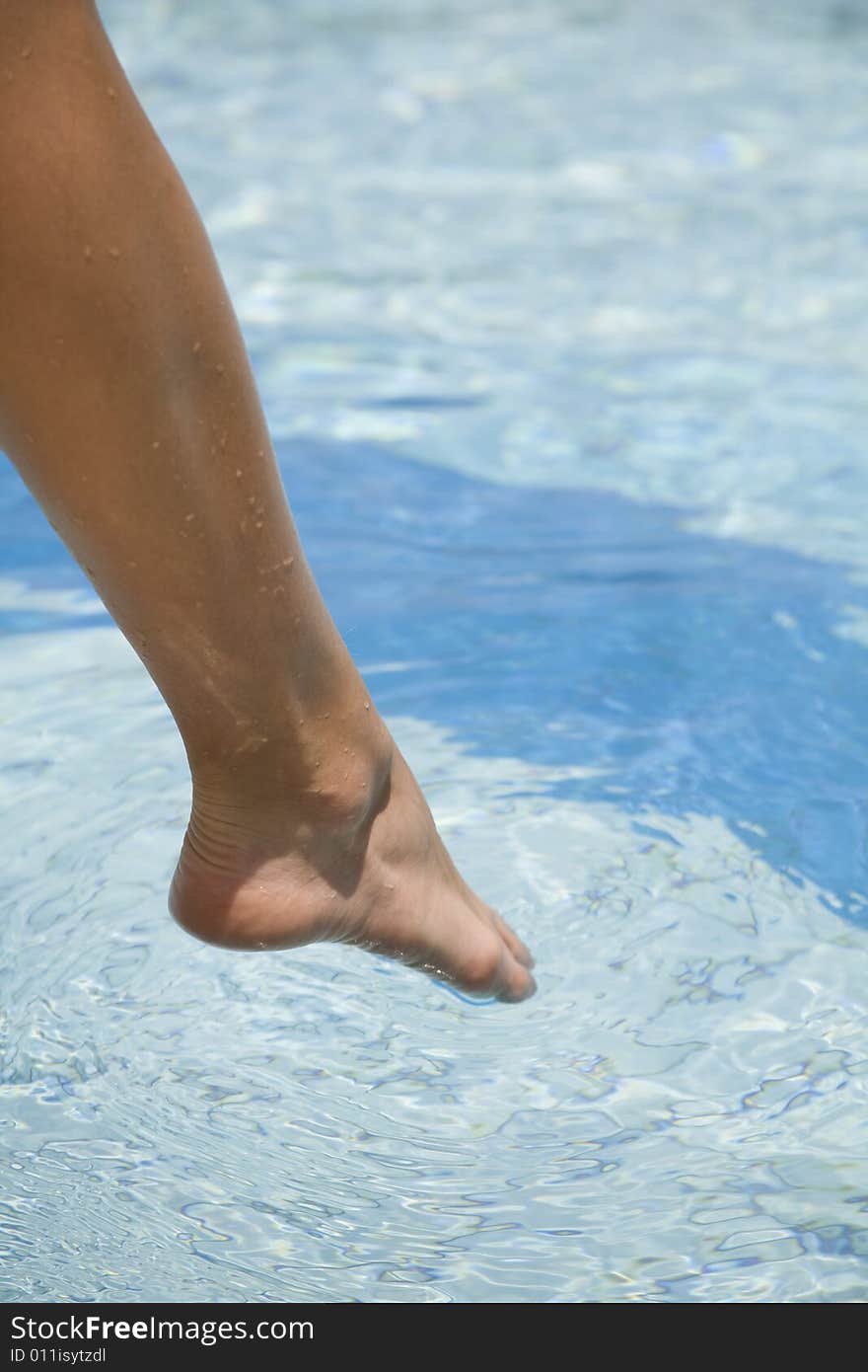 Feet step into the clear water swimming pool. Feet step into the clear water swimming pool