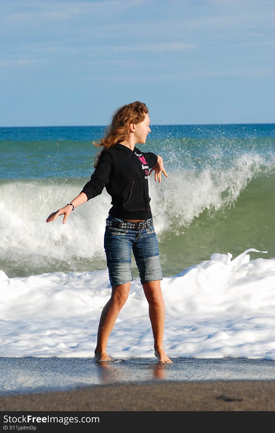 Joyful girl play on coast of ocean