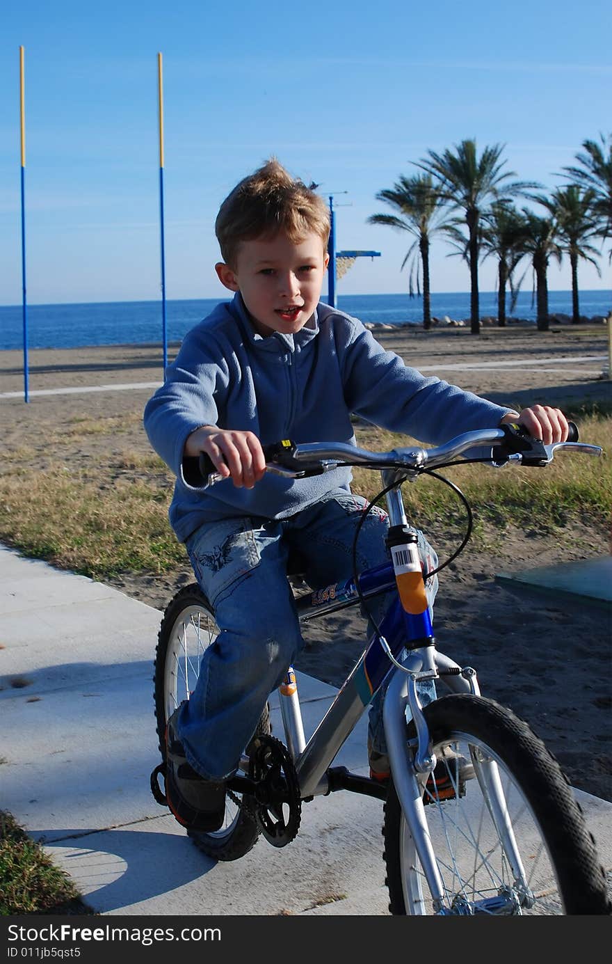 The happy boy goes for a drive on a bicycle