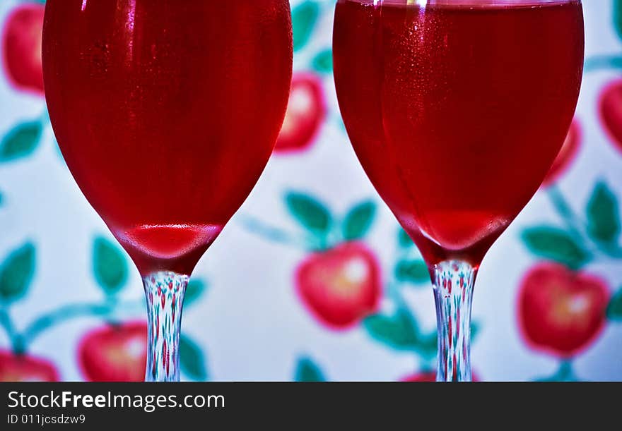 Two cold red drinks in wine glasses. Decorative wallpaper background. Two cold red drinks in wine glasses. Decorative wallpaper background.