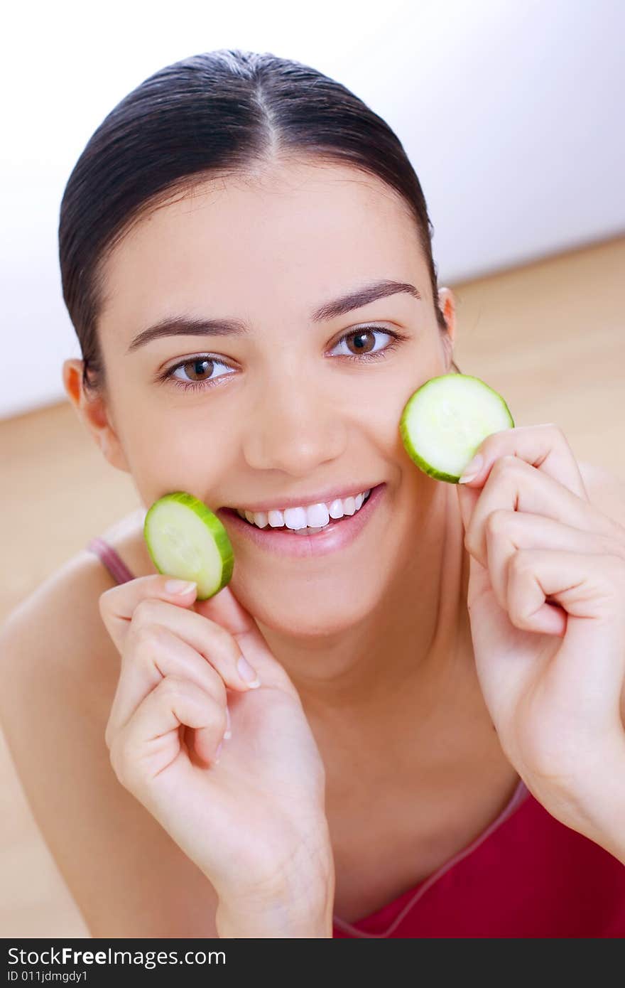 Woman holding cucumber close her face