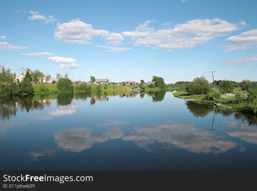 Village on the bank of the river and its reflection in the water