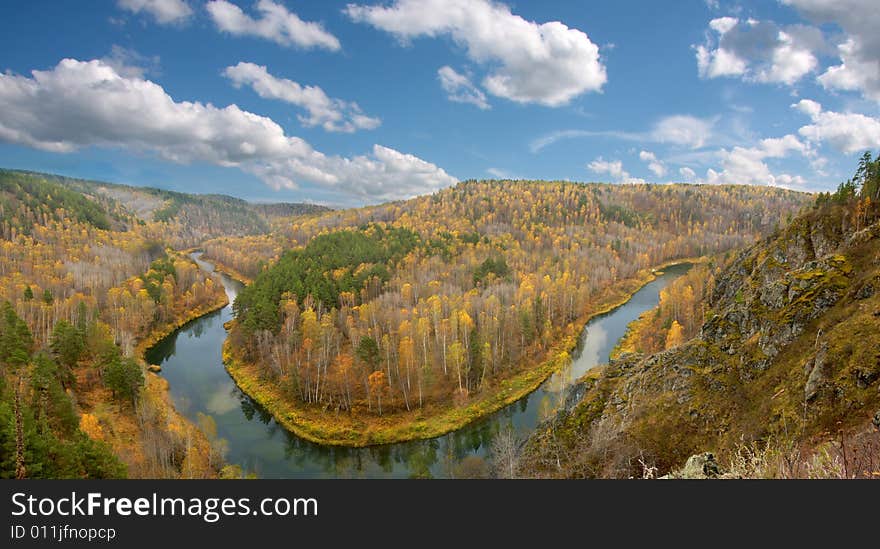 There is bright tranquil day and golgen leaves. River makes a turning around hill. There is bright tranquil day and golgen leaves. River makes a turning around hill.