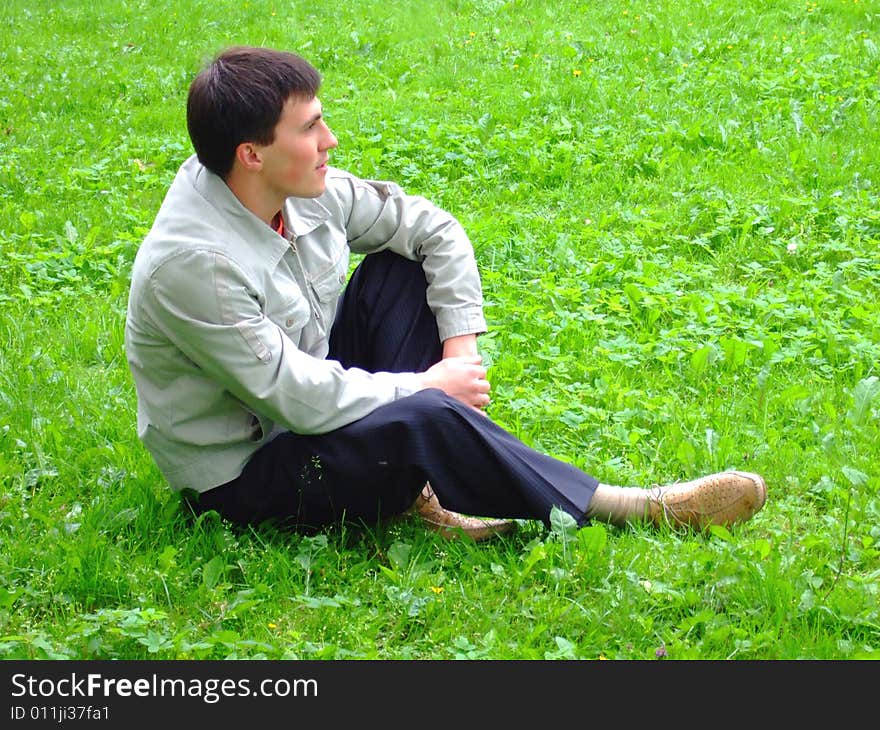 Thoughtful young man on a grass.