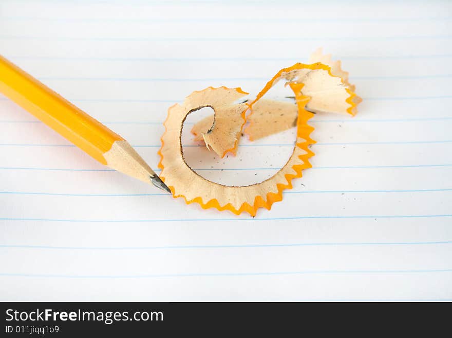 Pencil with shavings after being sharpened on a piece of notebook paper. Pencil with shavings after being sharpened on a piece of notebook paper.