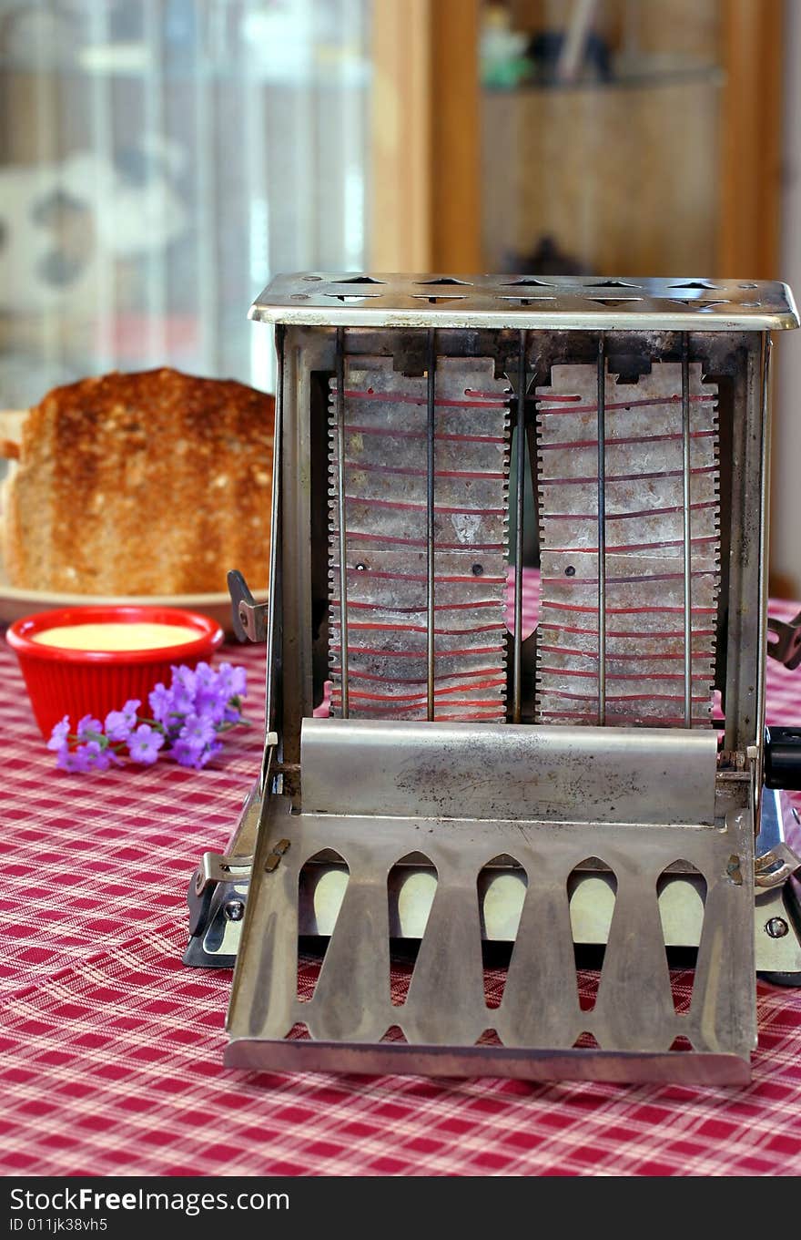 Vintage, working toaster with red elements on a table with toast, butter and flowers. Vintage, working toaster with red elements on a table with toast, butter and flowers.