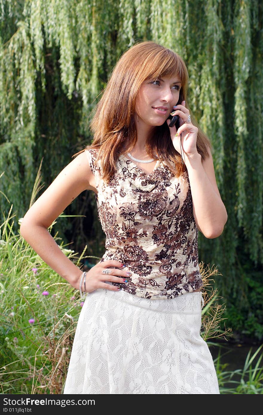 Young beautiful woman with chestnut-coloured hair is talking by the mobile. Young beautiful woman with chestnut-coloured hair is talking by the mobile