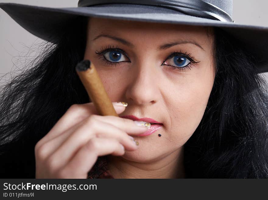 An image of woman in the hat smokes cigars