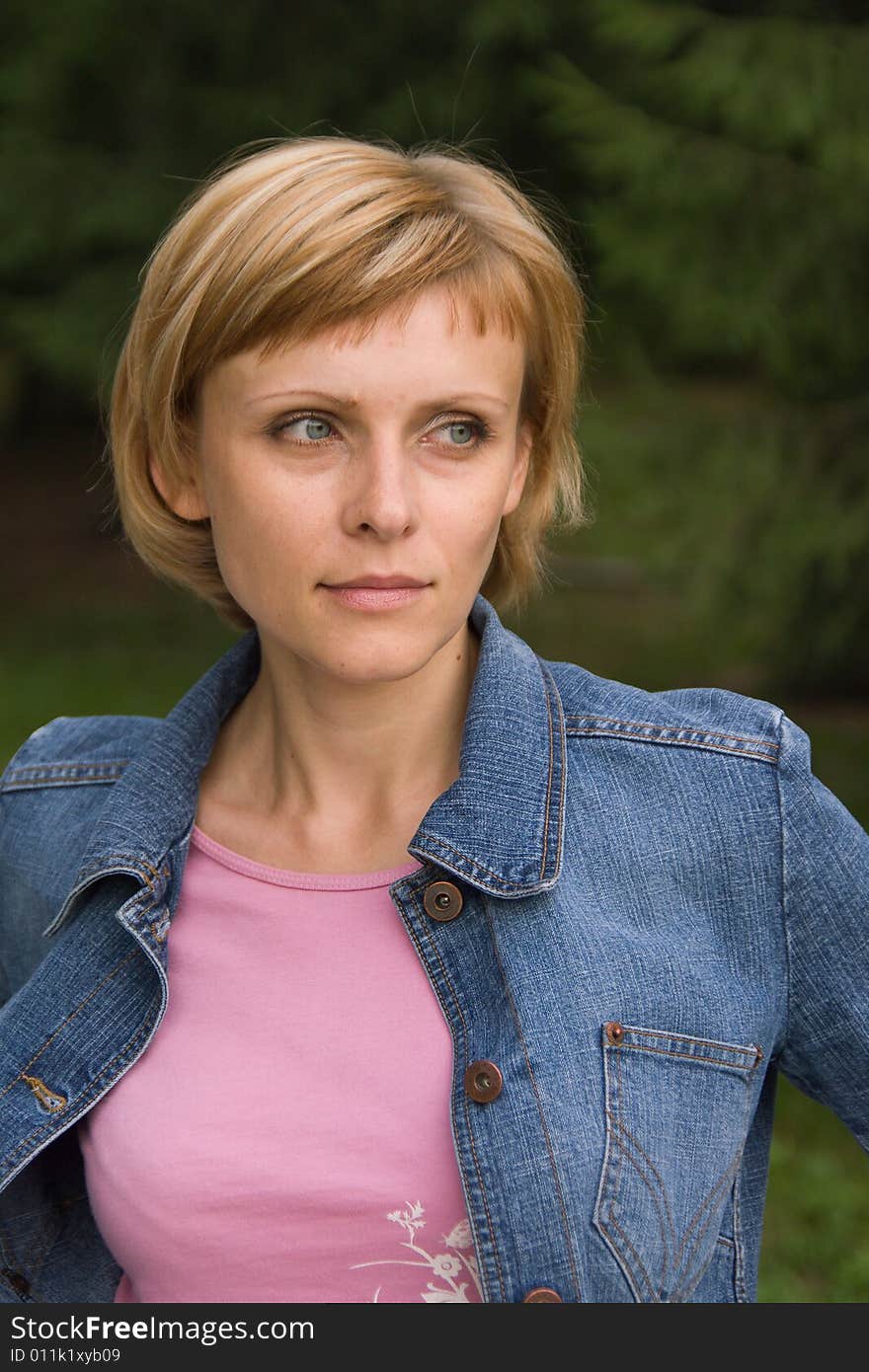 Young cute woman in a denim jacket looking at something. Young cute woman in a denim jacket looking at something