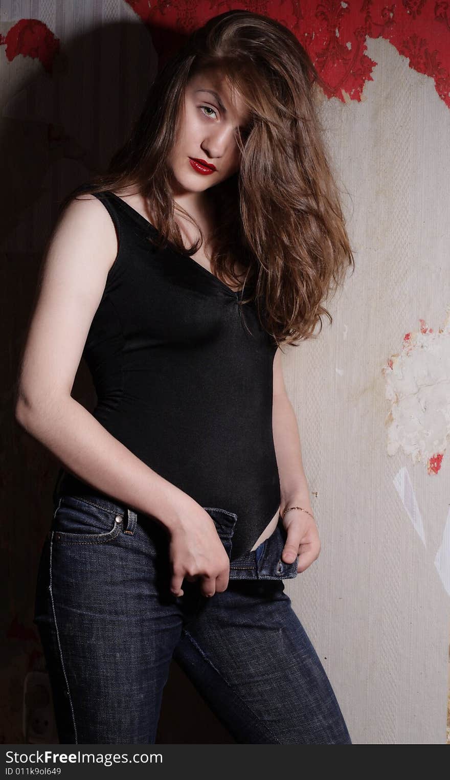 Beauty Girl in Jeans and Body on Grunge Wall Background