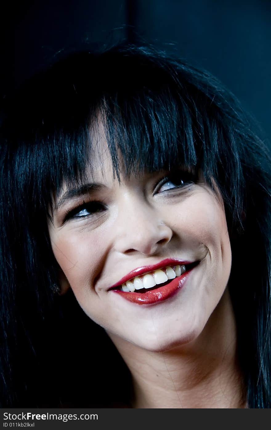 Head and bare shoulders of a young lady with black hair and red lipstick smiling. Head and bare shoulders of a young lady with black hair and red lipstick smiling.