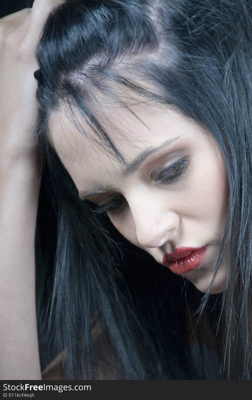 Head and shoulders of a young lady with black hair and red lipstick looking serious with hand on head. Head and shoulders of a young lady with black hair and red lipstick looking serious with hand on head.