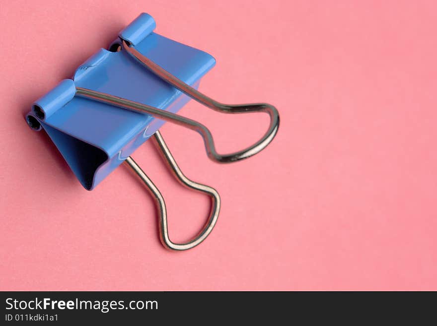 Close-up of blue metal paperclip on pink background. Close-up of blue metal paperclip on pink background