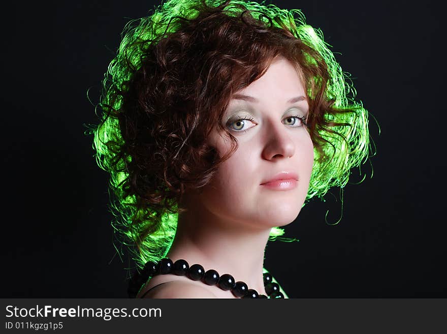 Beauty portrait of woman with green light on hair at black background