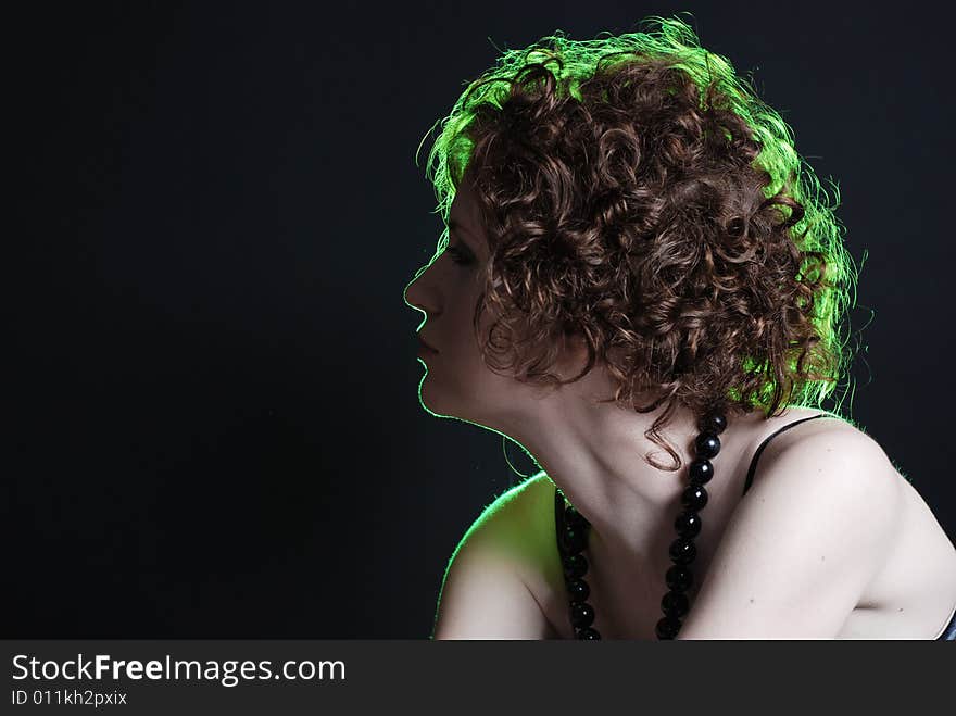 Beauty portrait of woman with green light on hair at black background