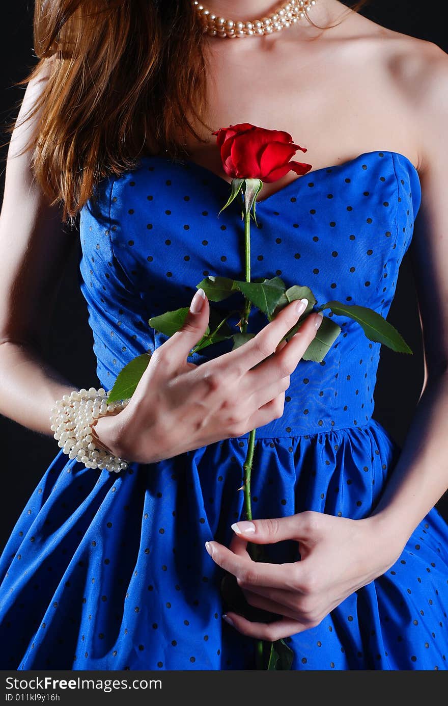 Beauty young woman in blue dress with rose at black background