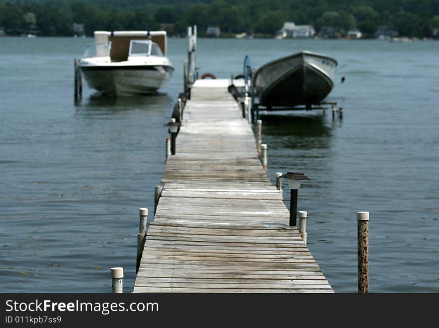 Two boats in dock on a lake.  Are they not moving due to high gas prices?  Or perhaps this is the ultimate staycation!