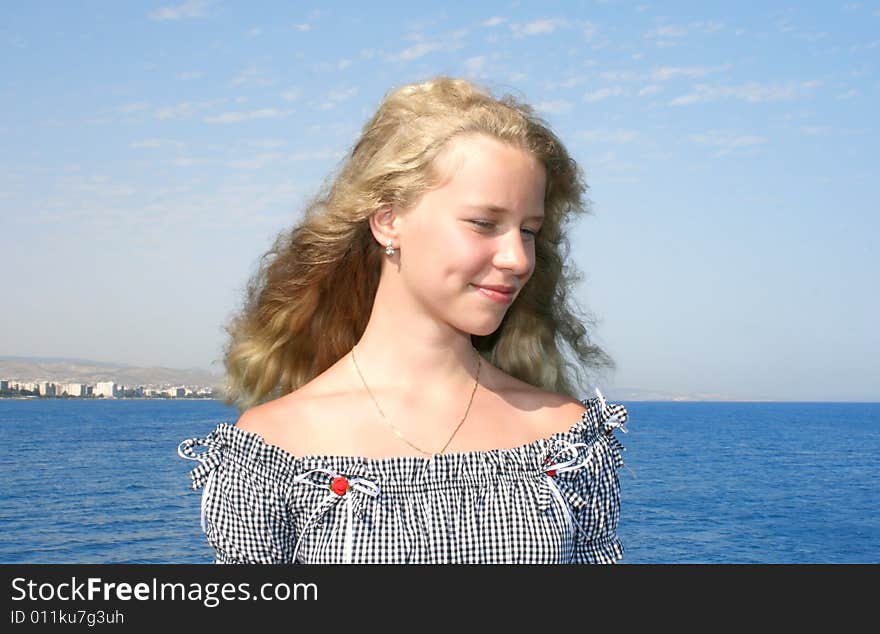 Pretty blond girl with long hair at the sea.