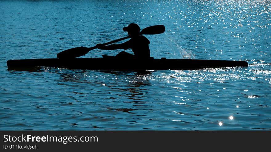 A black silhouette of a sportsman on a paddle (kayak). A black silhouette of a sportsman on a paddle (kayak)