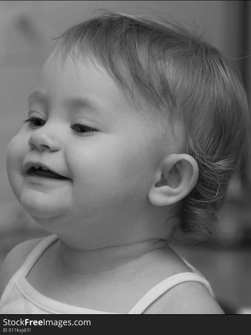 Black and white side portrait of cute baby girl laughing.