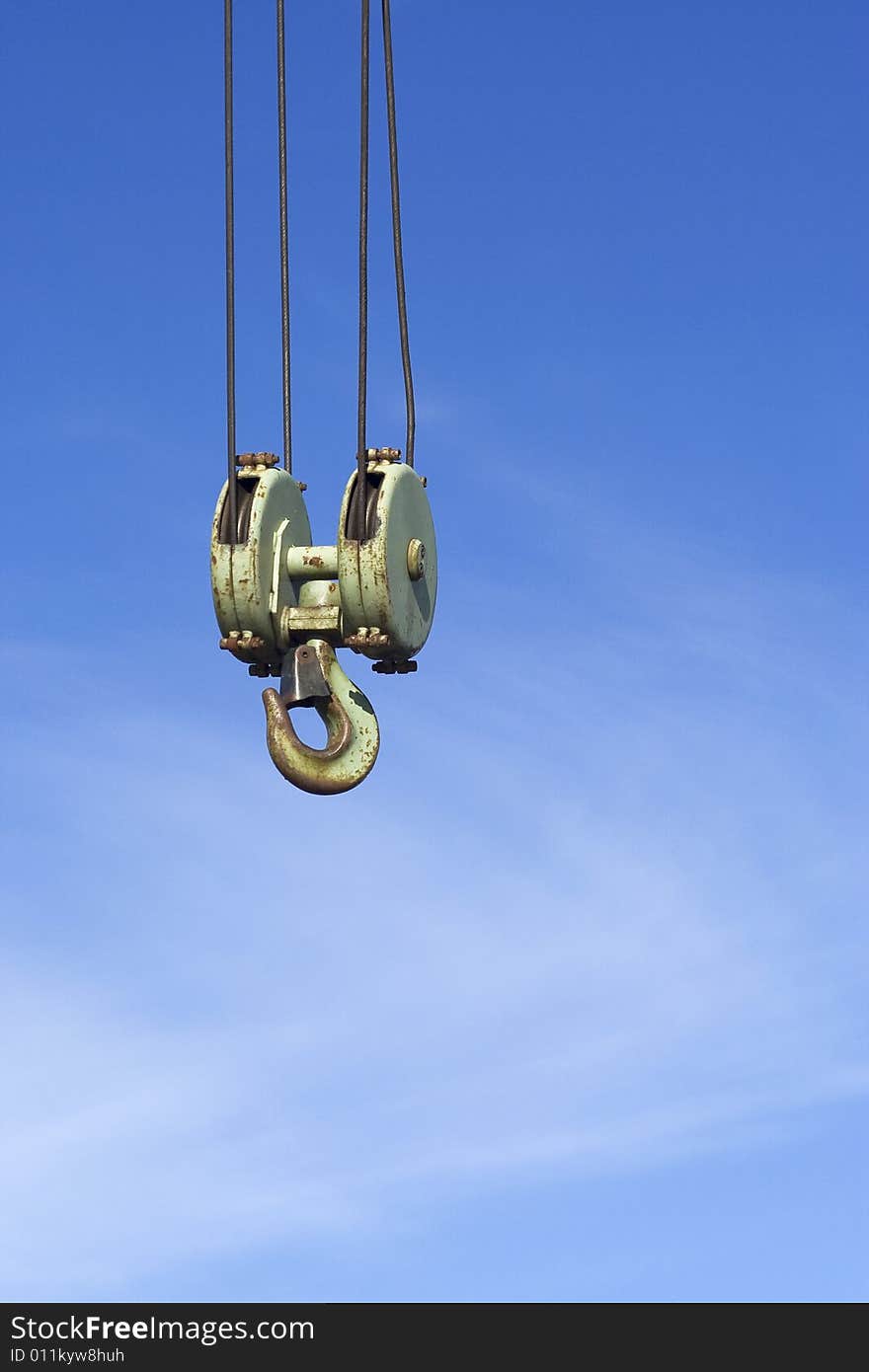 Green crane hook against the blue sky