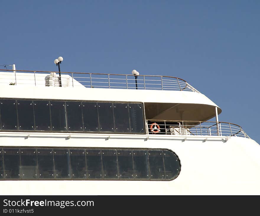 Upper deck of a white cruise liner with cabin windows