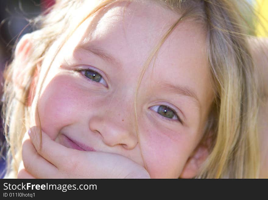 Smiling six year old girl with the sun shining in her hair.