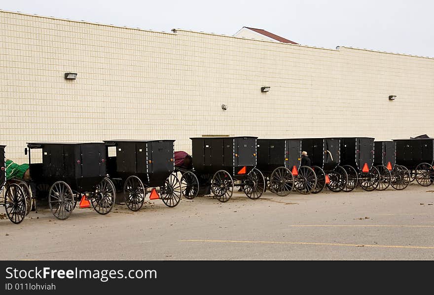 Amish horse-drawn buggies parked in modern supermarket parking lot. Amish horse-drawn buggies parked in modern supermarket parking lot