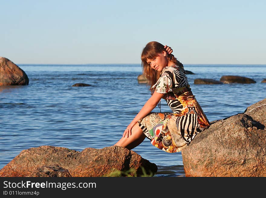 Young lady sitting on stones and smoothes her hair. Young lady sitting on stones and smoothes her hair