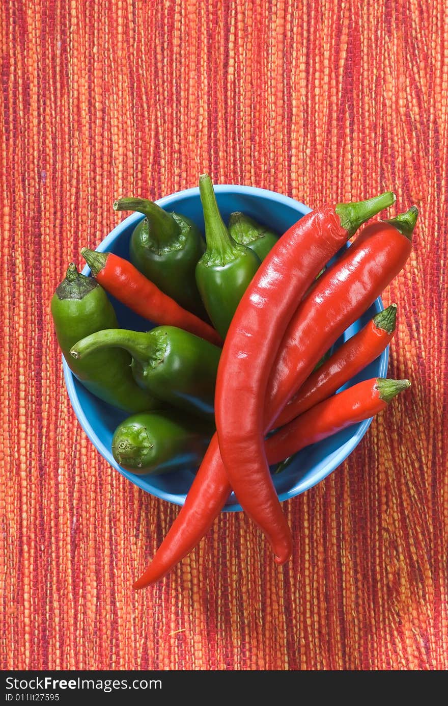 Overhead view of red and green chili peppers in a bowl