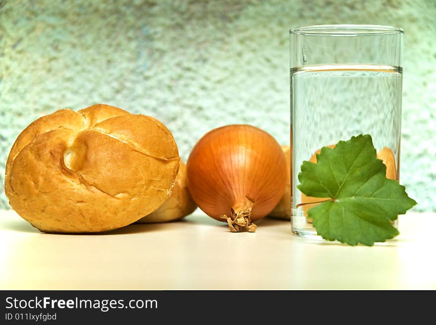 Bread roll, onion and glass of water. Bread roll, onion and glass of water.