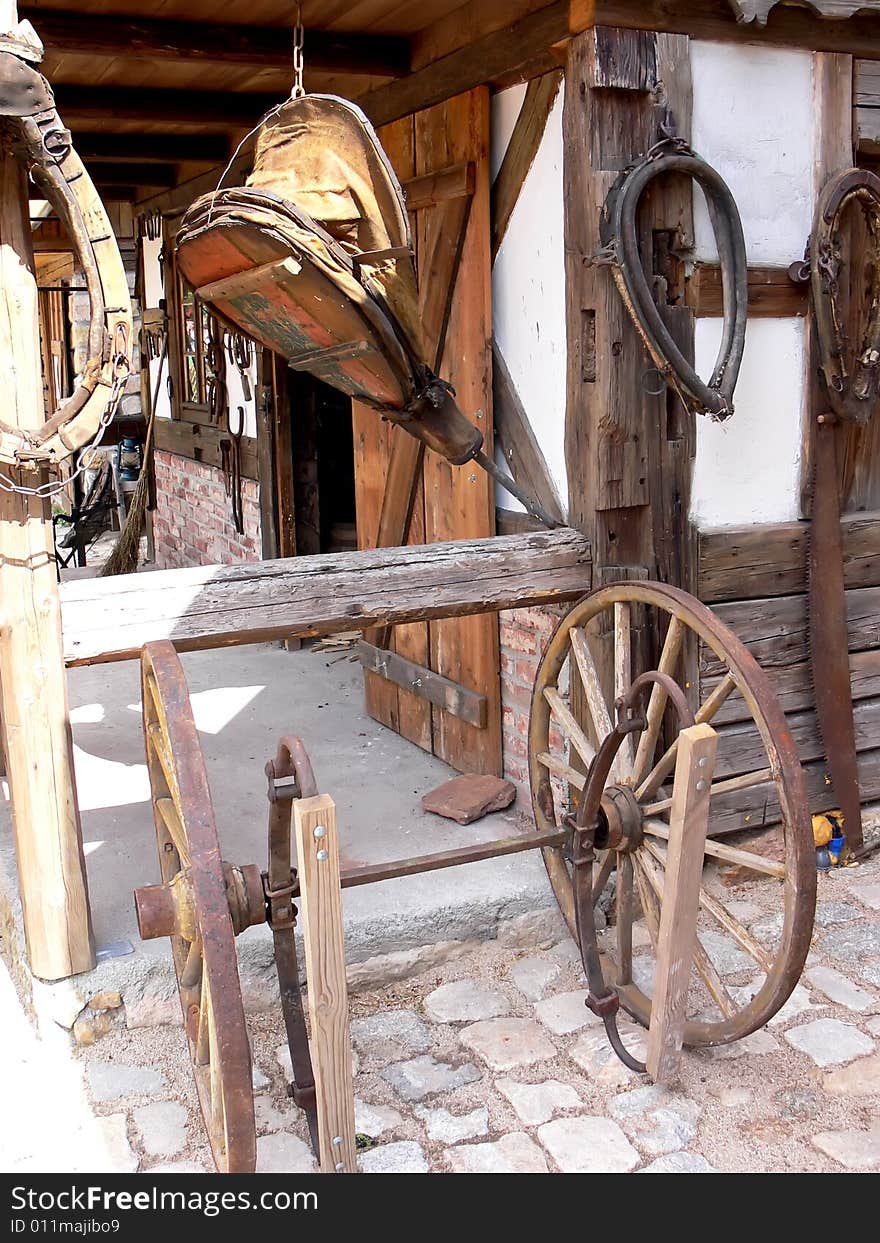 A view at the blacksmith workshop. Old bellows,  wooden wheels and horse items. A view at the blacksmith workshop. Old bellows,  wooden wheels and horse items.