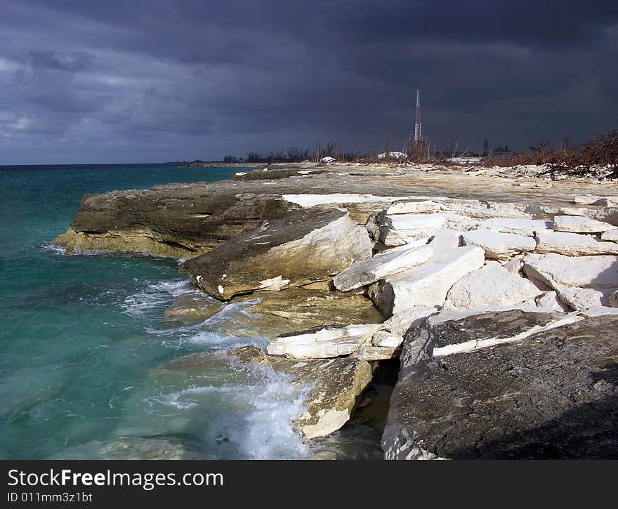 The view of eroded hostile beach in Freeport with stormy sky in a background (Grand Bahama Island, The Bahamas). The view of eroded hostile beach in Freeport with stormy sky in a background (Grand Bahama Island, The Bahamas).