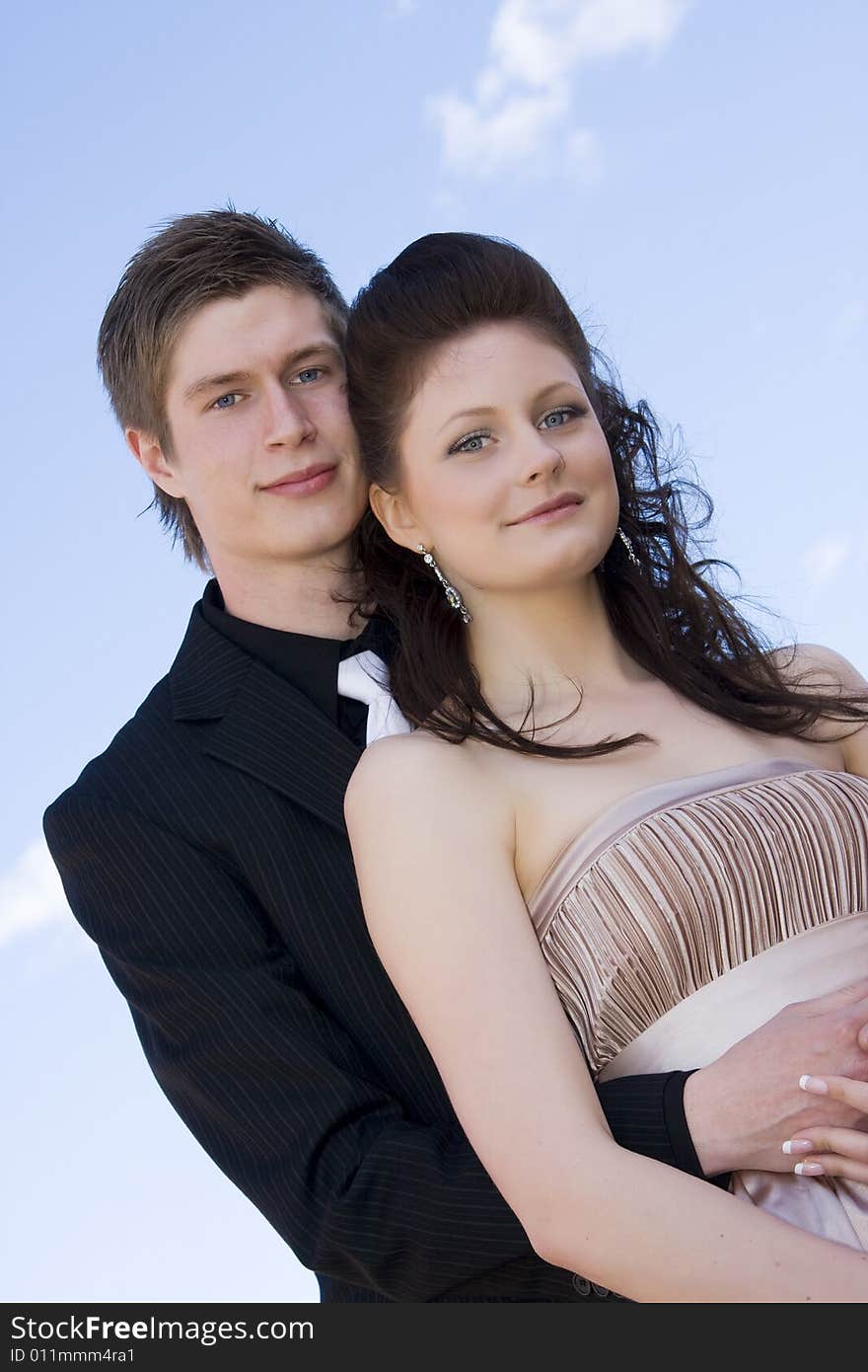 Young beautiful happy couple on sky background