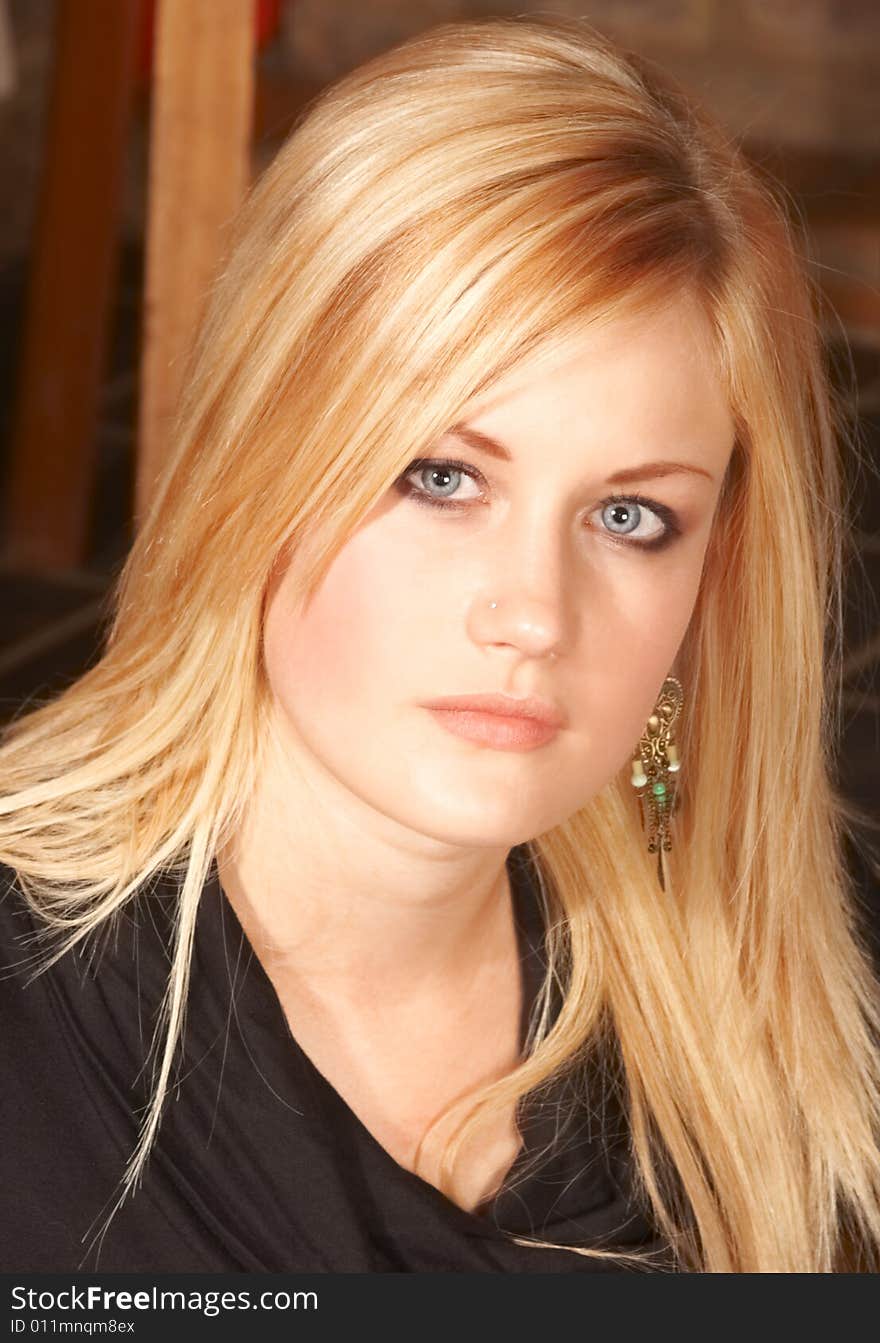 Portrait of Blonde beautiful girl with bright blue eyes and serious look in black top. Portrait of Blonde beautiful girl with bright blue eyes and serious look in black top