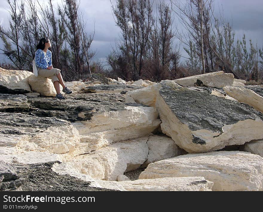 The girl enjoys sunlight on eroded beach in Freeport on Grand Bahama Island, The Bahamas. The girl enjoys sunlight on eroded beach in Freeport on Grand Bahama Island, The Bahamas.