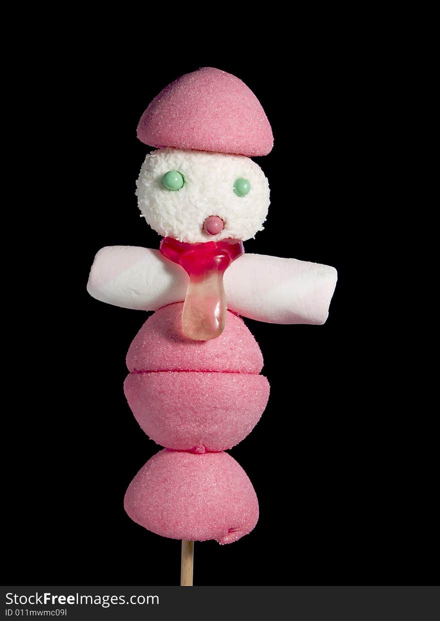 A male figurine made out of candies on a stick over a black background. A male figurine made out of candies on a stick over a black background.