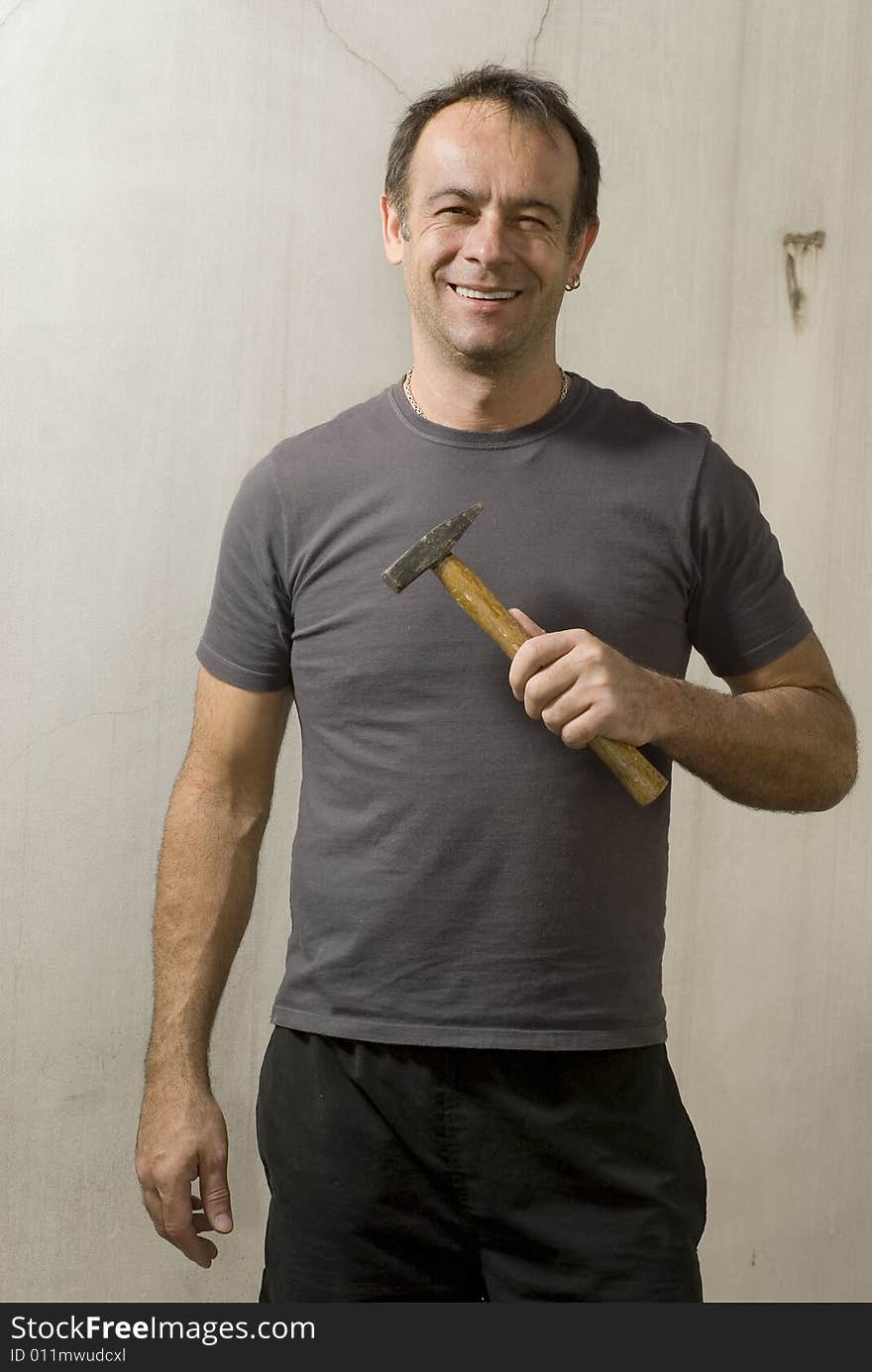 Man smiling while holding hammer and looking at camera. Vertically framed shot. Man smiling while holding hammer and looking at camera. Vertically framed shot.