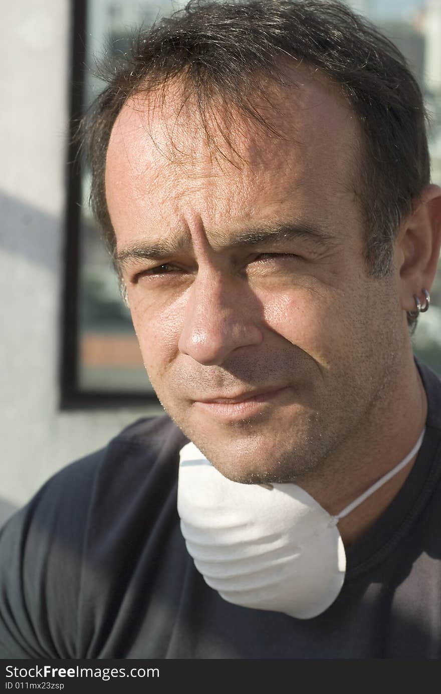 Close up of man's face. He is wearing a mask around his neck. He is looking concerned or thoughtful. Vertically framed shot. Close up of man's face. He is wearing a mask around his neck. He is looking concerned or thoughtful. Vertically framed shot.