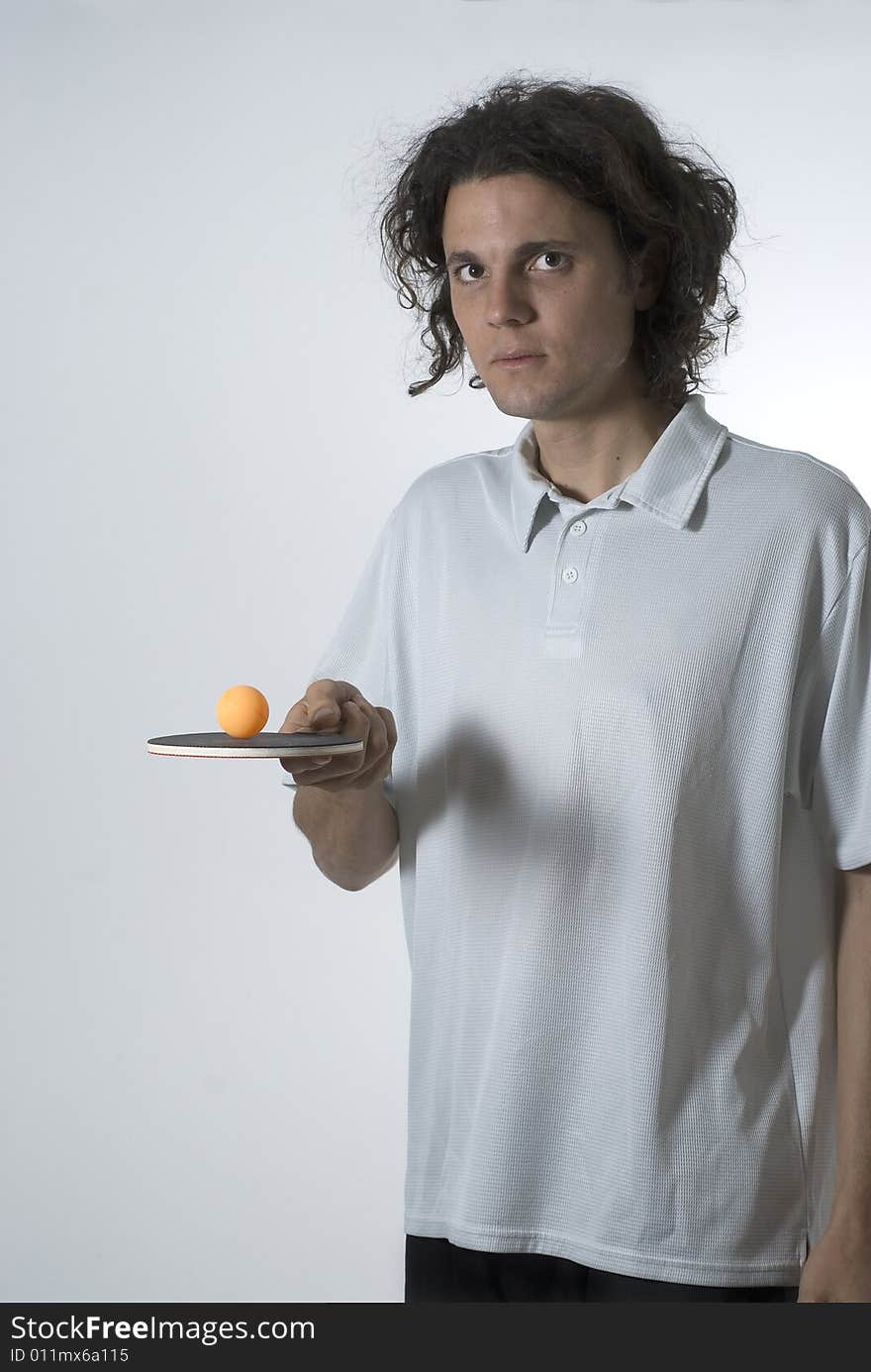 Man holding a ping pong paddle and balancing a ball on top. He is looking at the camera. Vertically framed shot. Man holding a ping pong paddle and balancing a ball on top. He is looking at the camera. Vertically framed shot.