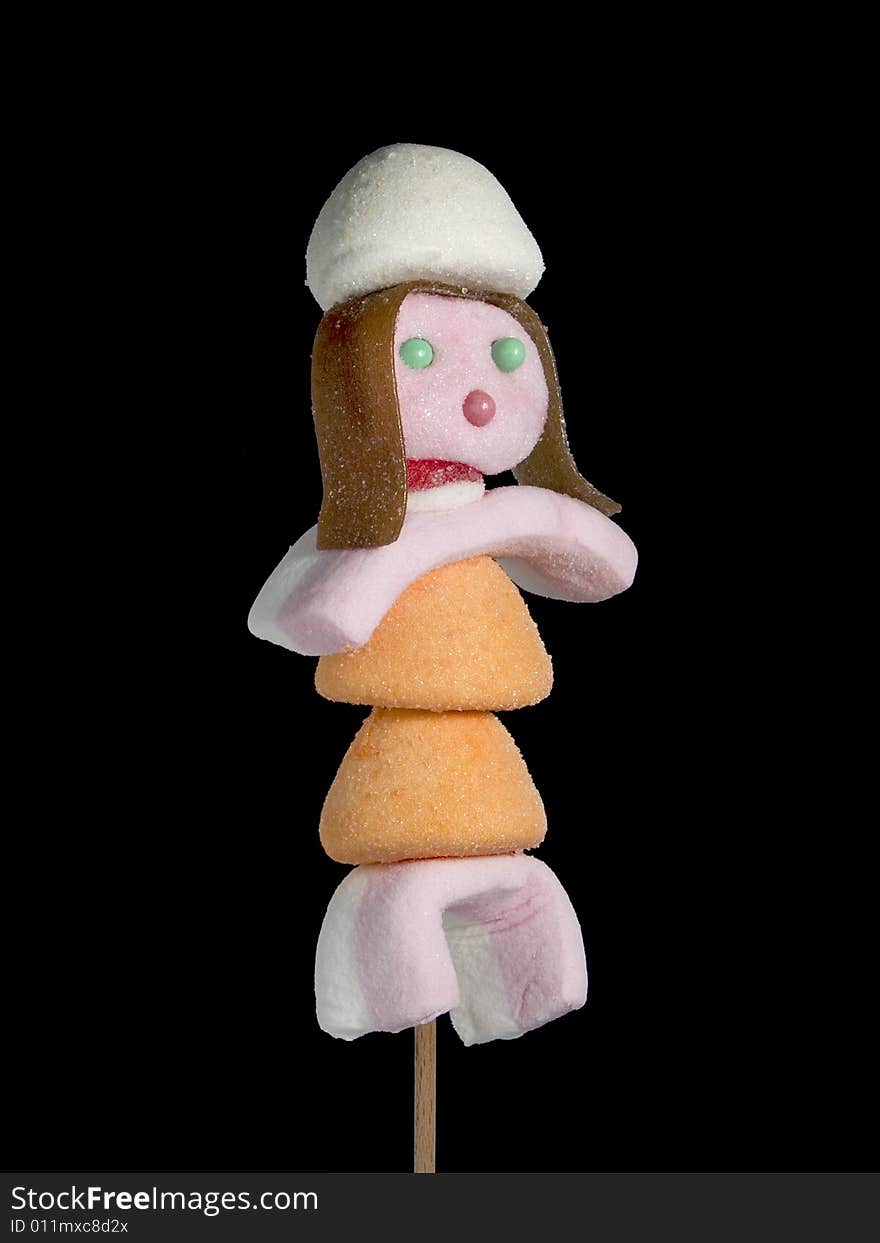 A female figurine made out of candies on a stick over a black background. A female figurine made out of candies on a stick over a black background.