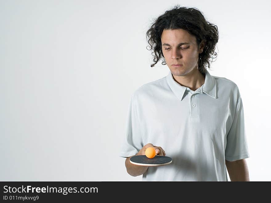 Man looks at a table tennis racket and ball as he balances it. Horizontally framed photograph. Man looks at a table tennis racket and ball as he balances it. Horizontally framed photograph