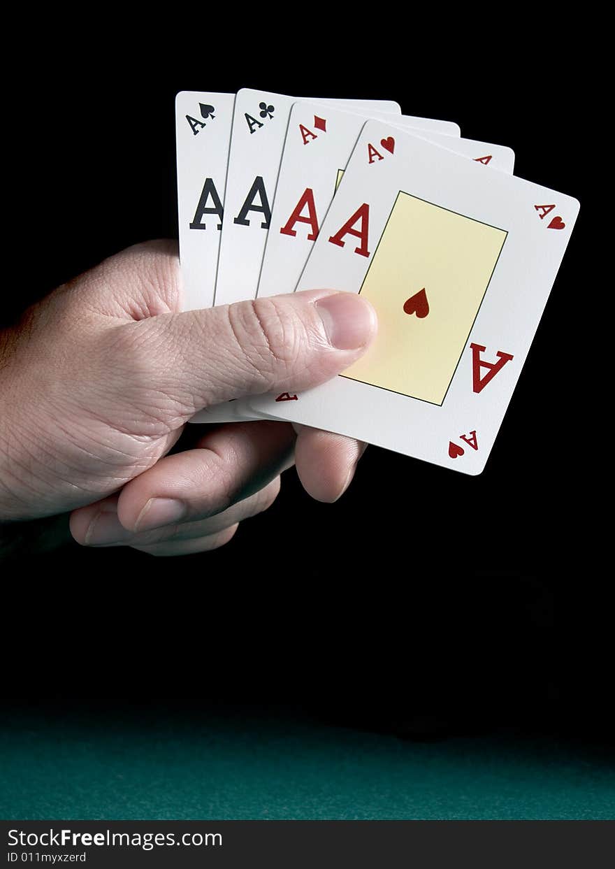 A man's hand holding four aces isolated on black background.