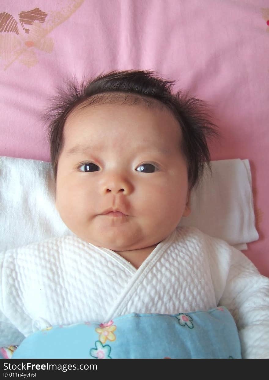 An infant on a bed, big eyes opening