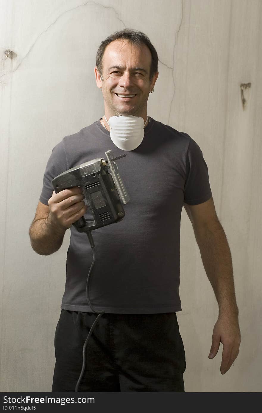 Man standing holding jigsaw with mask around neck. He is looking at camera and smiling. Vertically framed shot. Man standing holding jigsaw with mask around neck. He is looking at camera and smiling. Vertically framed shot.