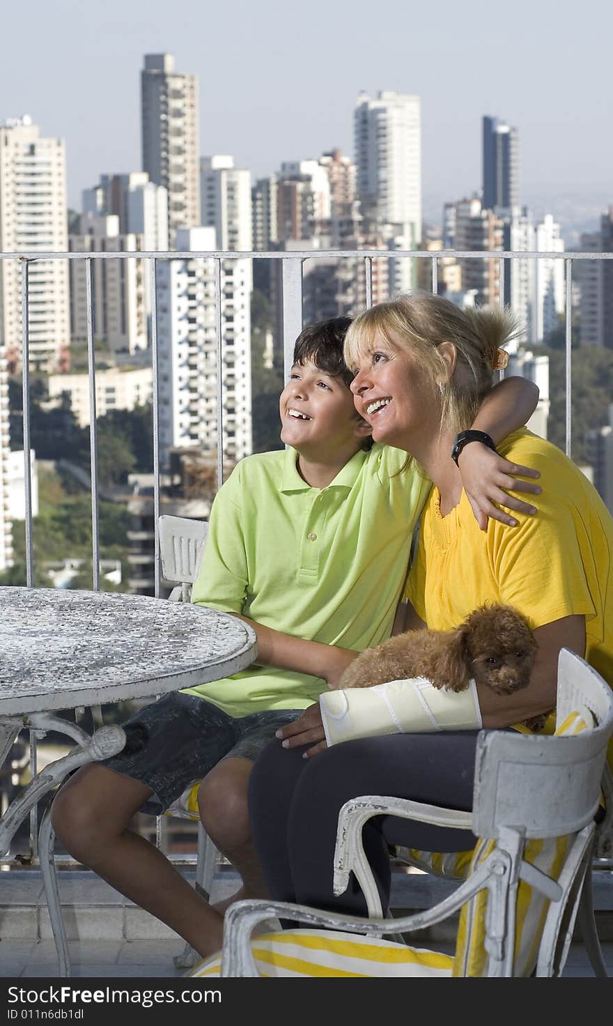 Boy sitting with woman. Boy with arm around woman. Woman wearing cast and holding dog. Vertically framed photo. Boy sitting with woman. Boy with arm around woman. Woman wearing cast and holding dog. Vertically framed photo.