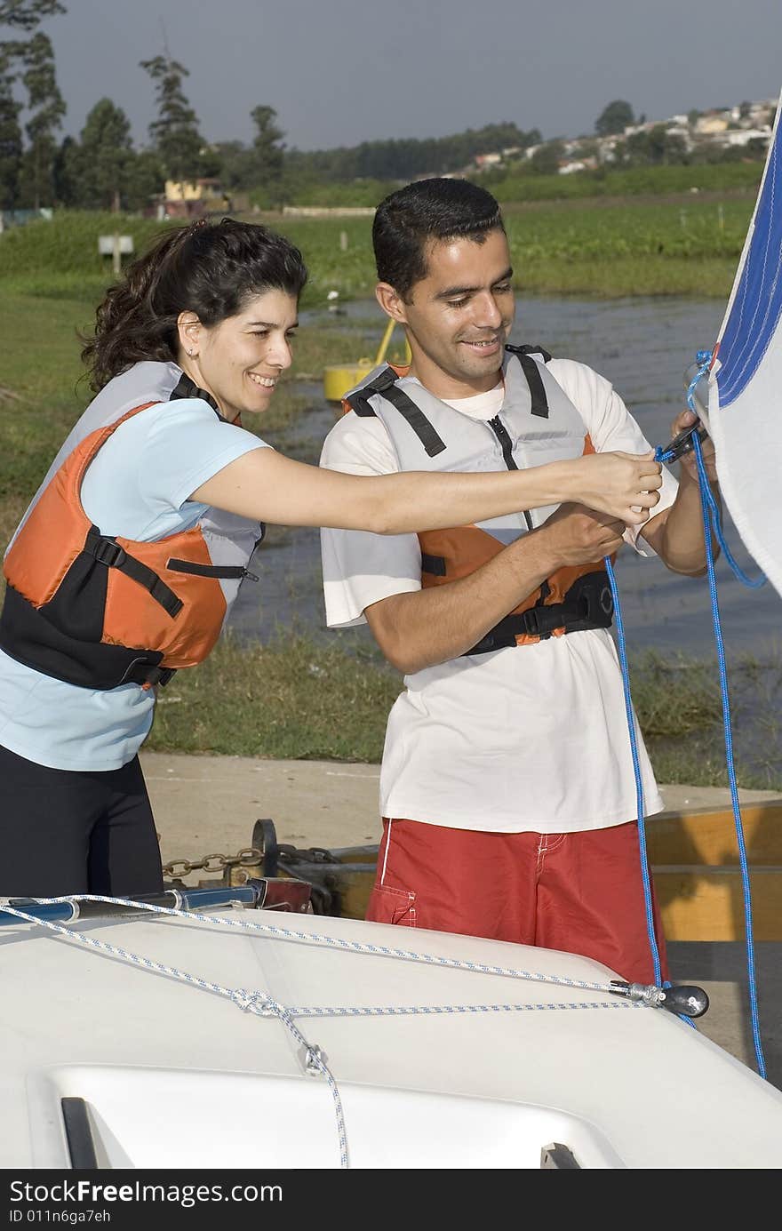 Man and woman smiling while rigging sails on sailboat. Working Together. Vertically framed photo. Man and woman smiling while rigging sails on sailboat. Working Together. Vertically framed photo