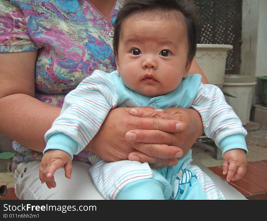 Big eyes infant on her grandmother's leg