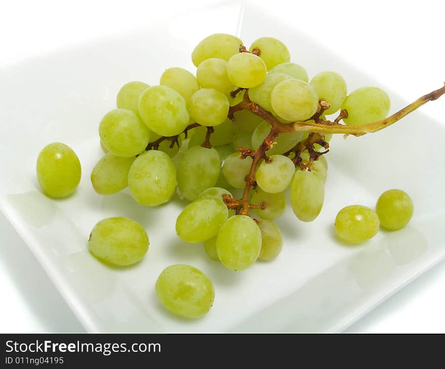 Fresh bunch of green grapes in white bowl and isolated on white background